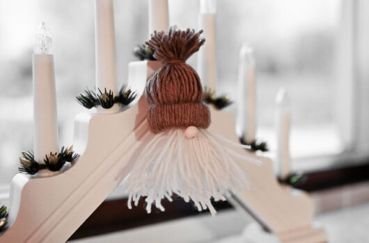 Jultomte i garn vid ljusstake.