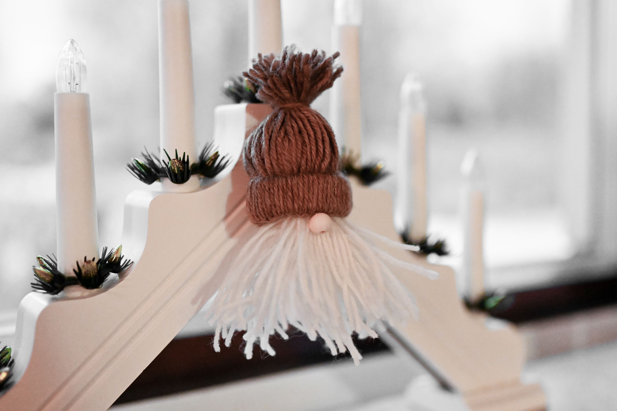 Jultomte i garn vid ljusstake.